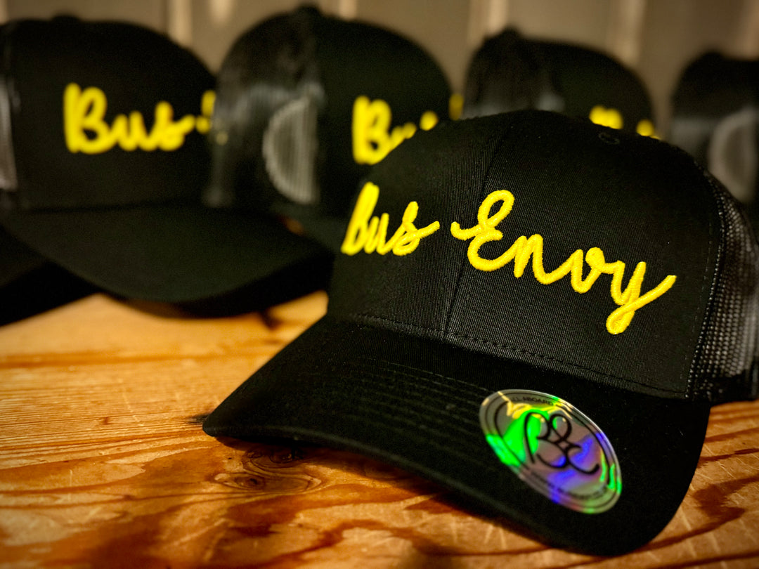 Snap Back Trucker Cap. All black. Yellow 3D logo